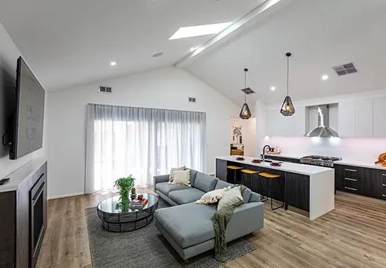 Open-plan living and kitchen area with a high cathedral ceiling and pendant lighting