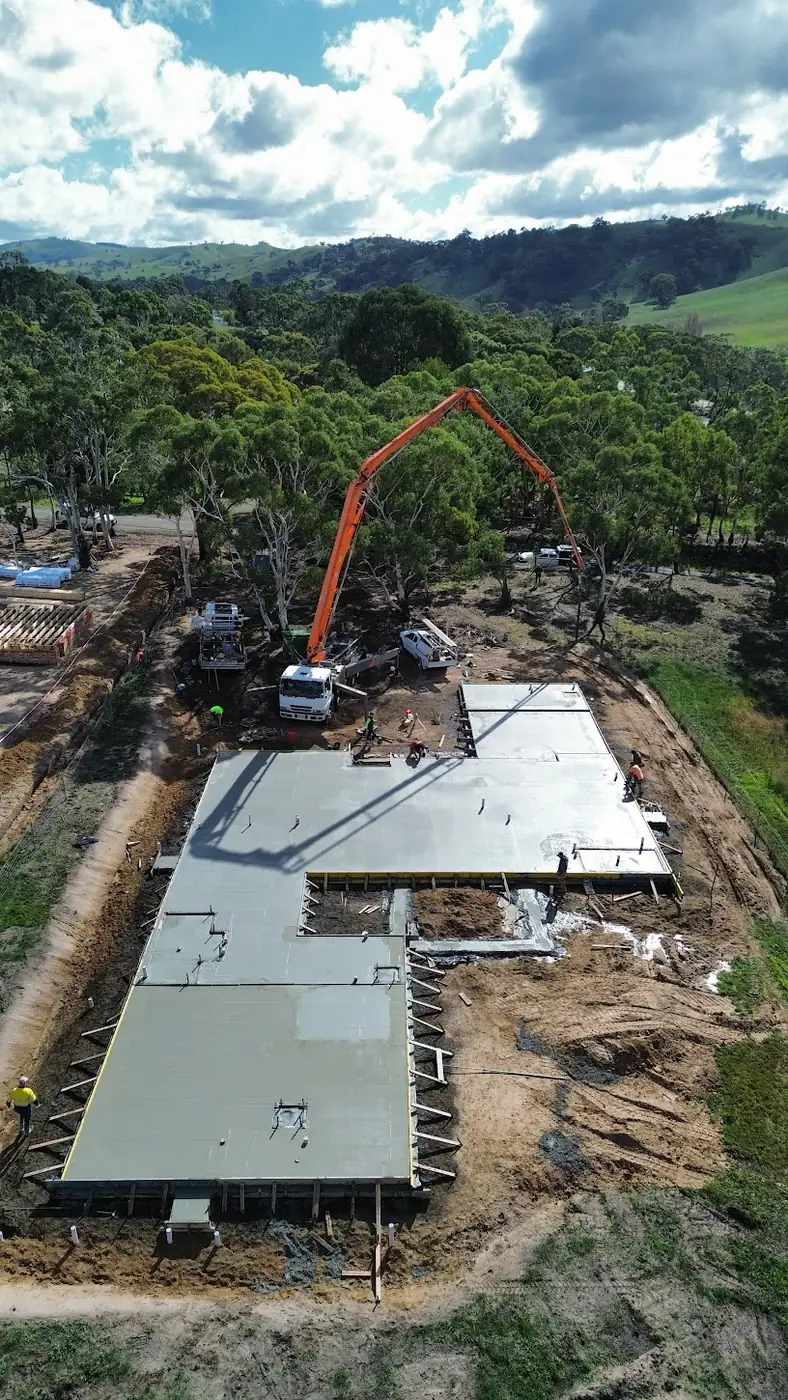 Aerial view of a concrete slab being poured for a new home on a rural block