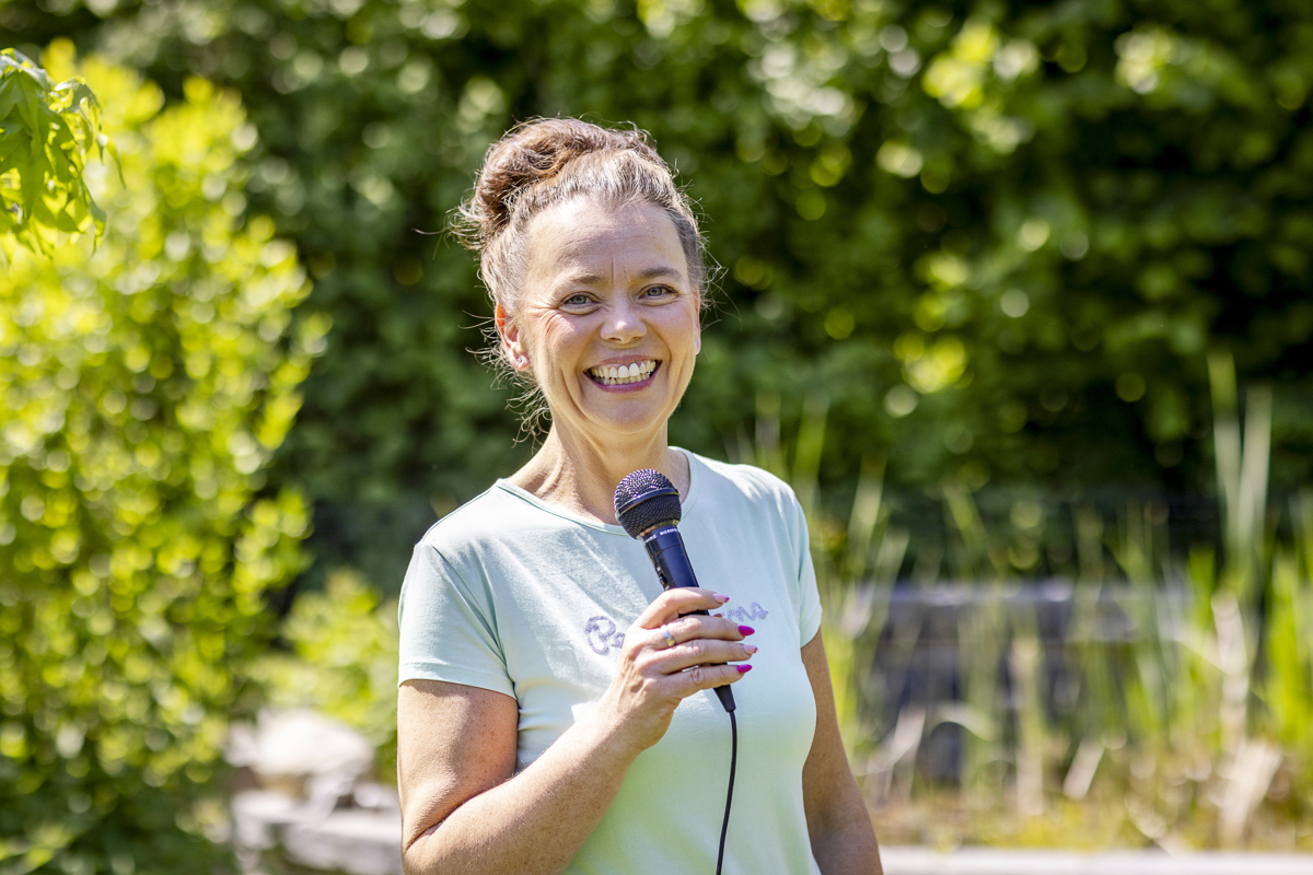 Kati Kreyser, freie Rednerin, mit Mikrofon bei einer freien Trauung im Garten in Berlin und Brandenburg
