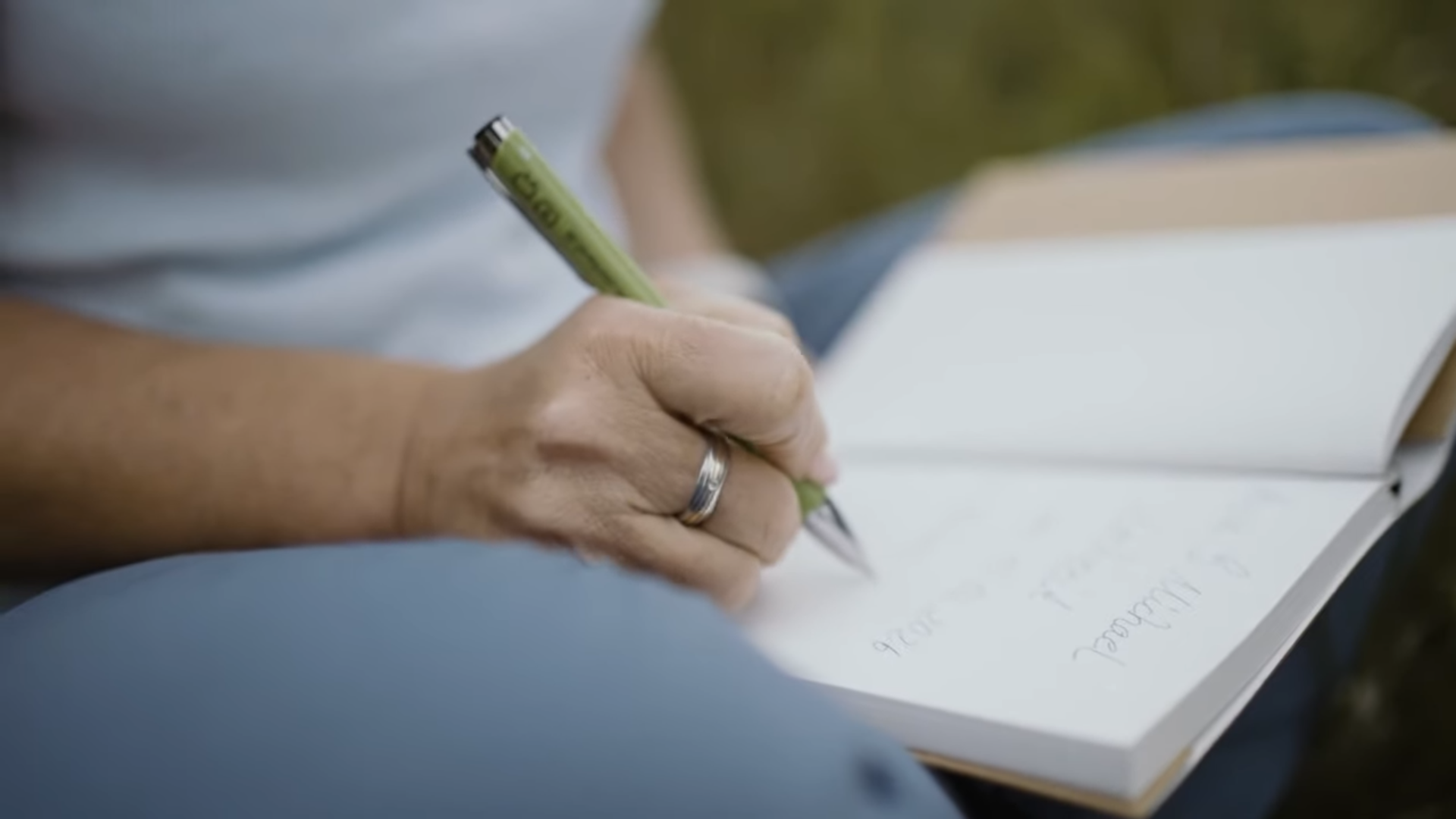 Kati Kreyser sitzt im Gras und schreibt Gedanken für eine Zeremonie in ihr Notizbuch