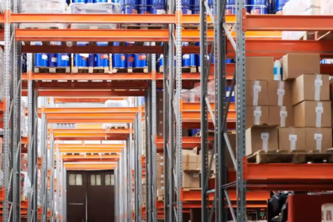 Warehouse shelves stocked with blue barrels and cardboard boxes