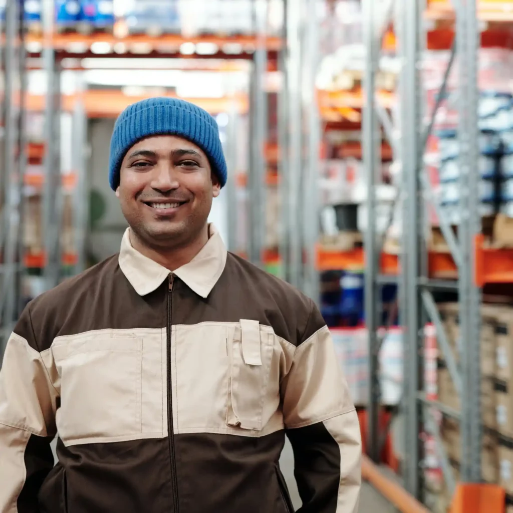 Smiling warehouse worker standing in storage aisles