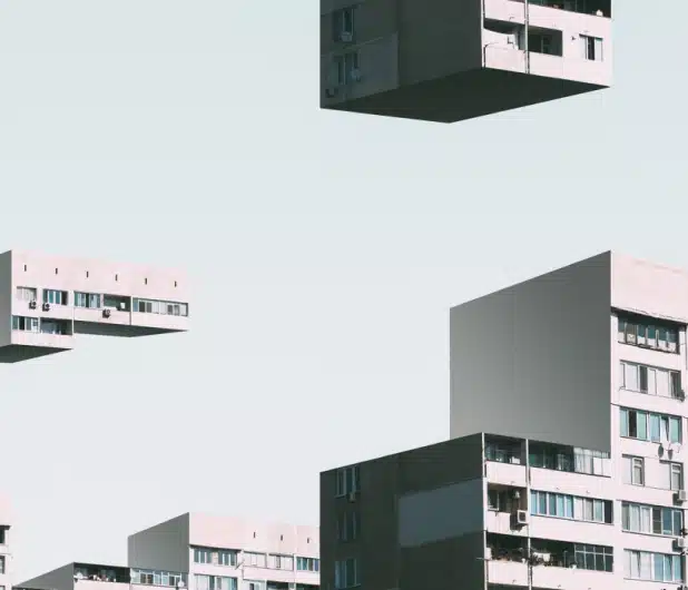 Floating cubes with apartment building facades against a pale sky