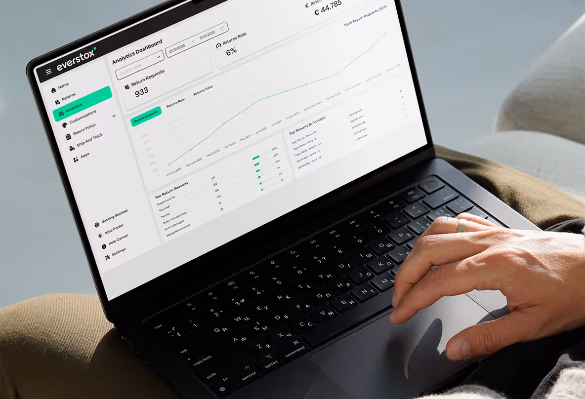 Hand using a laptop displaying an analytics dashboard for return requests and rates on the everstox platform.