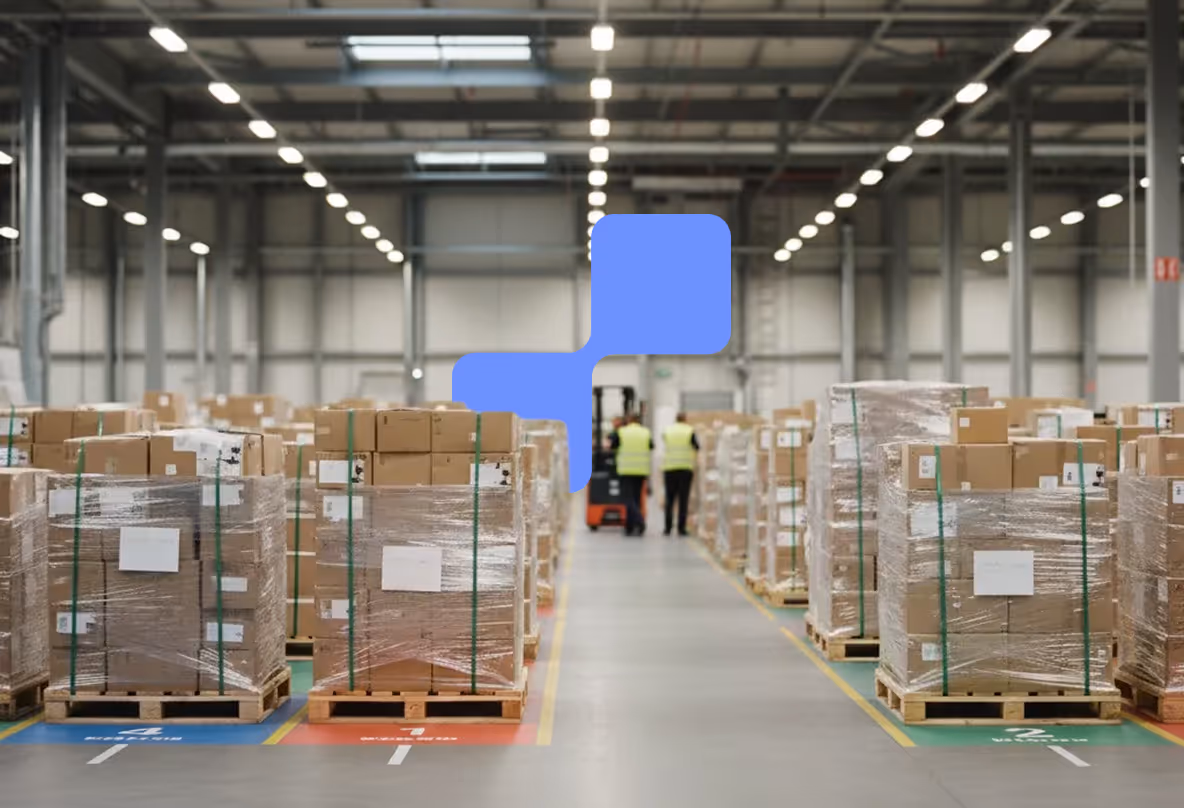 Warehouse aisle with pallets of wrapped cardboard boxes and two workers in yellow vests near a forklift in the background.