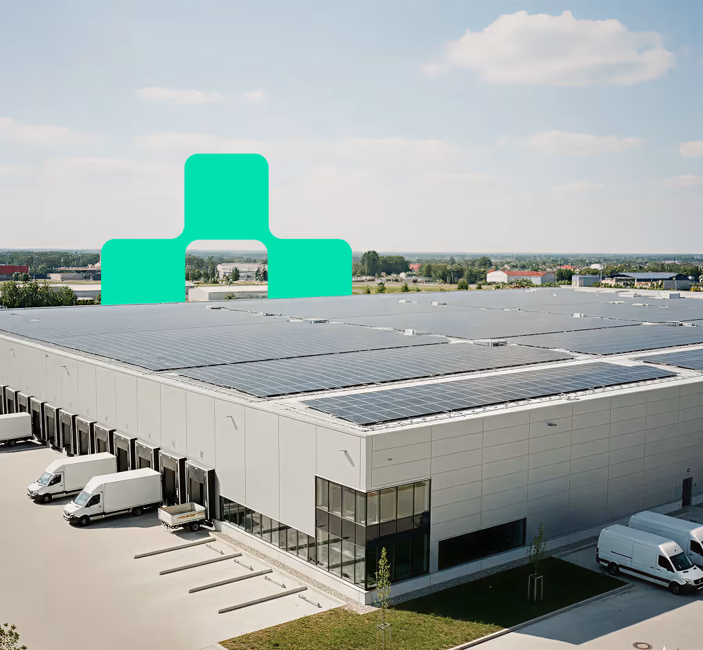 Large warehouse with solar panels on the roof and delivery trucks parked at loading docks