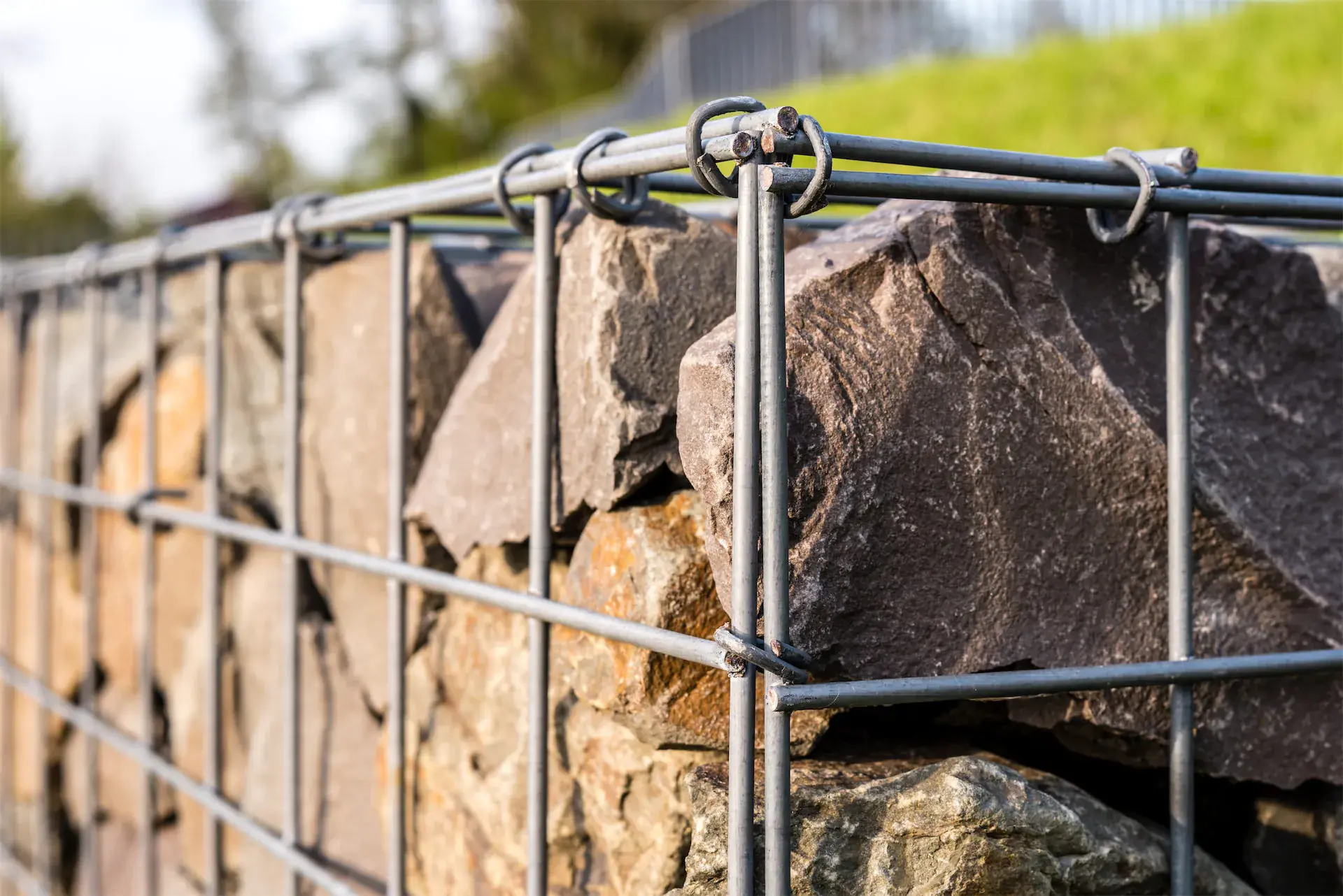 Gros plan d'un mur en pierres naturelles maintenues par une structure métallique en treillis.