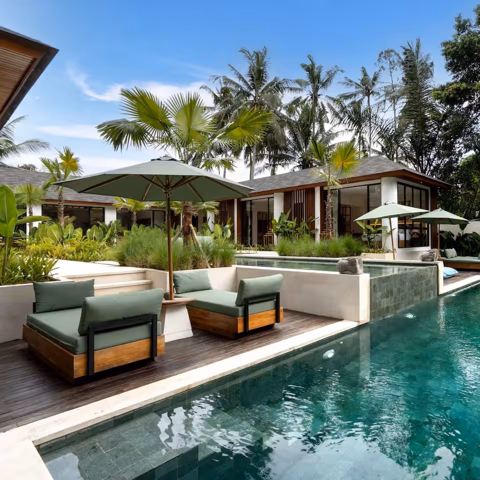 pool next to hotel with tables and chairs