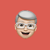 Emoji of an elderly man with gray hair, glasses, and a smiling expression on a red background.