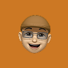 Smiling older man emoji wearing glasses and a brown flat cap on an orange background.