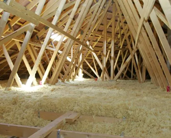 Grenier avec isolation en laine soufflée sur le plancher et structure en bois apparente.