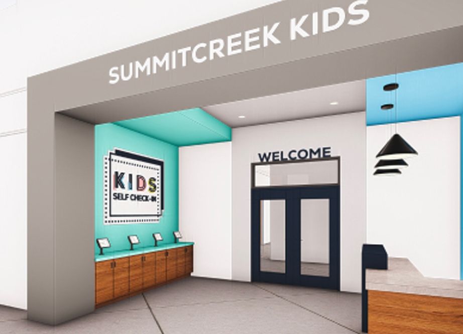 Entrance to SummitCreek Kids area with a self check-in station and welcome sign above double doors.
