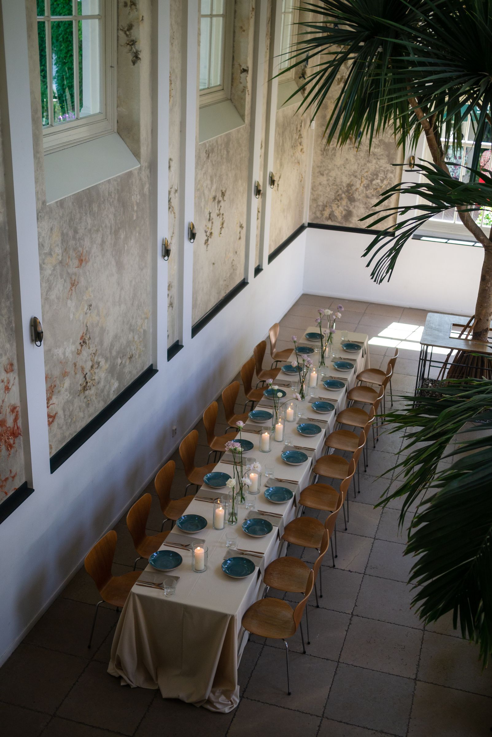 Long dinner table with candles and flowers in the orangery of the Hortus Botanicus