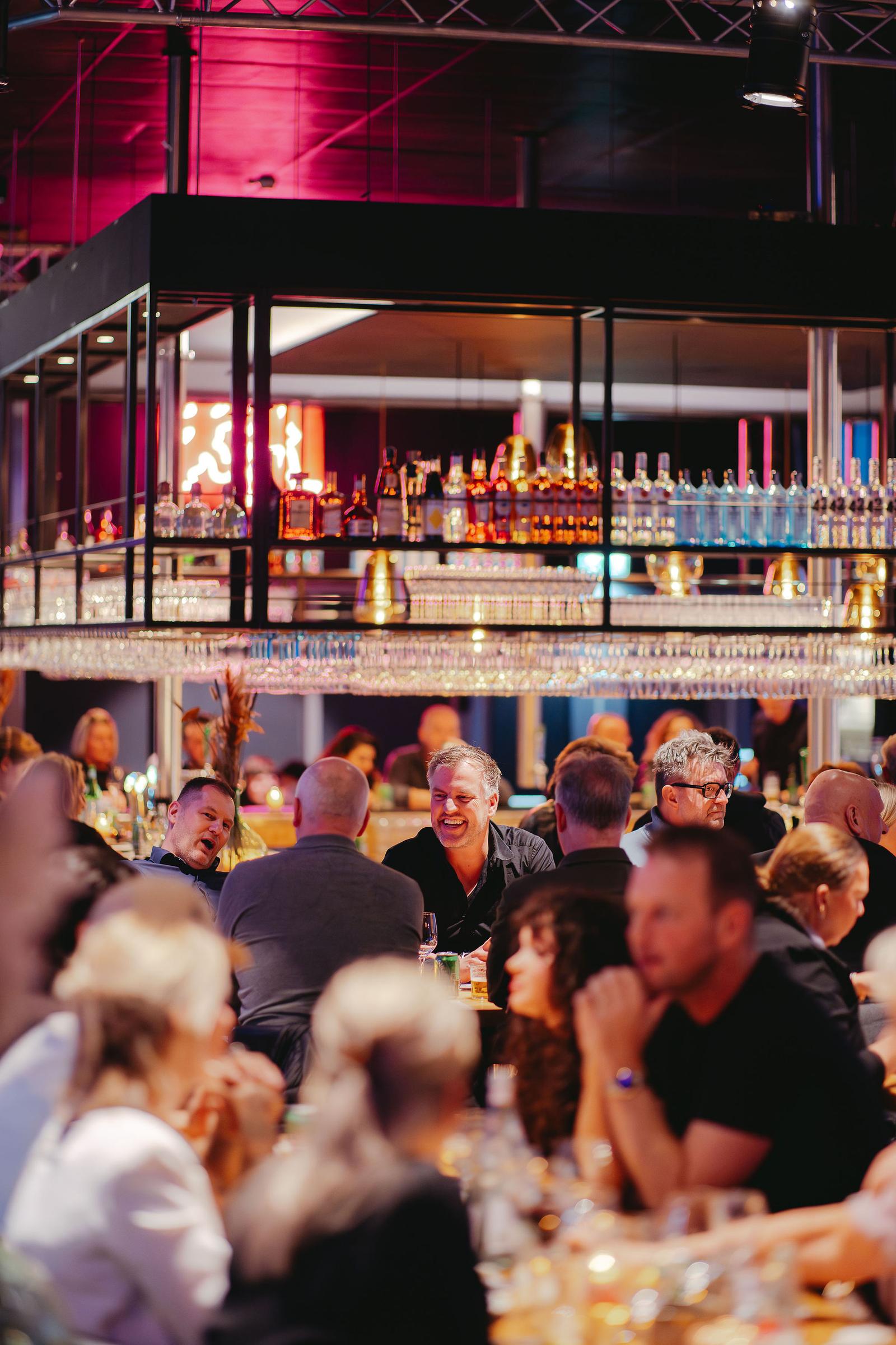 Gasten aan tafel onder de bar van BAUT Backstage