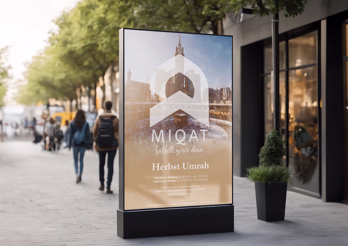 Outdoor advertisement board displaying MIQAT travel service for Herbst Umrah pilgrimage with a background image of the Kaaba in Mecca.