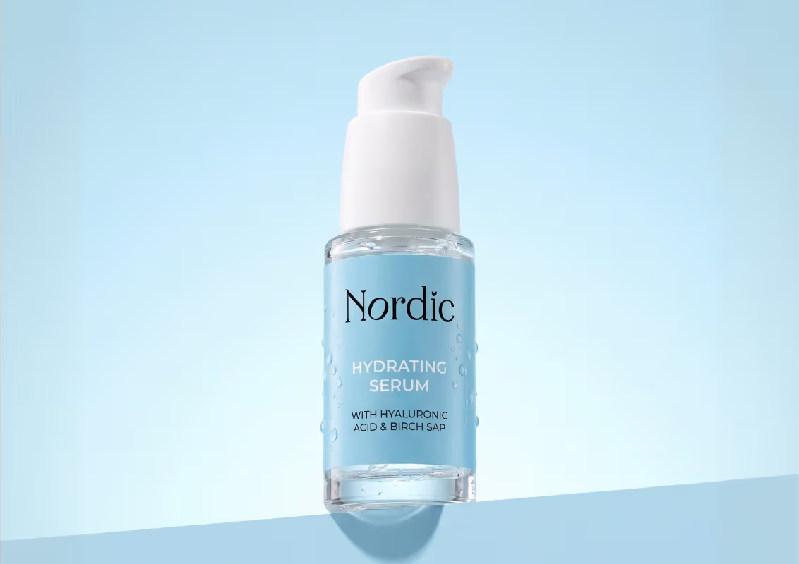 Bottle of Nordic Hydrating Serum with hyaluronic acid and birch sap on a light blue background.