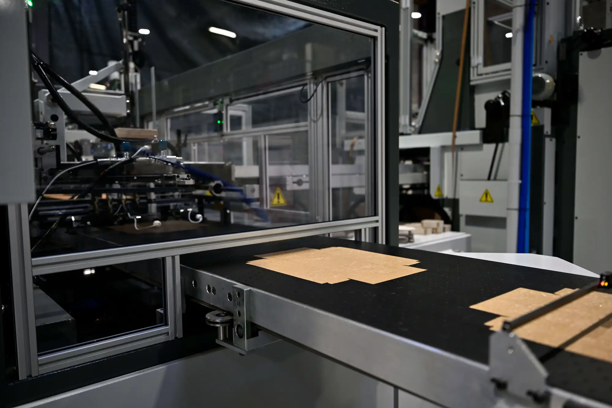 Machine industrielle découpant des feuilles de matériau sur une table de travail en usine.