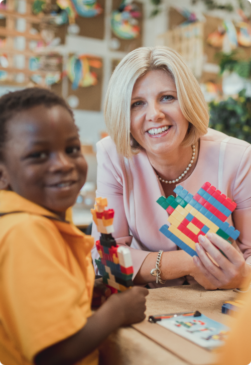 Lisa Rodgers sitting smiling with a child, holding toy blocks