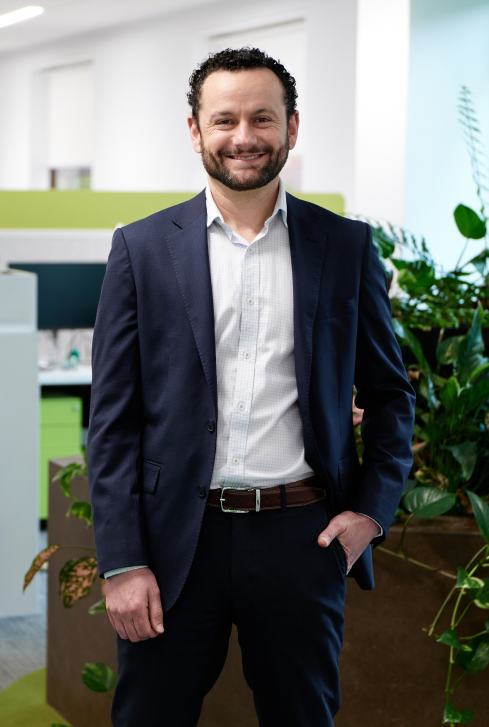 Dr Nathan Zoanetti posing for a photograph in front of a plant