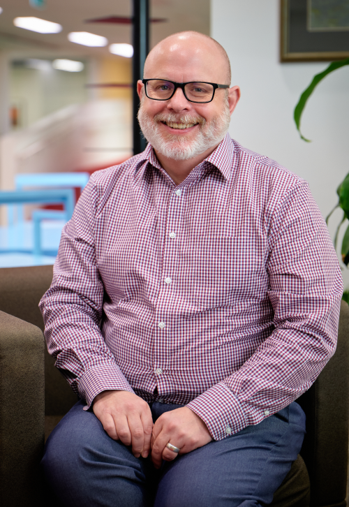 Colin Watson sitting on a chair smiling in an office setting