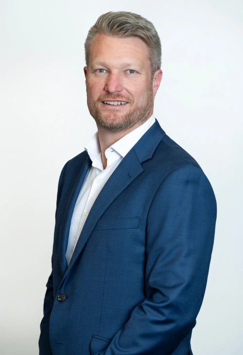 Dr Jarrod Hingston standing in a classroom with a nice dark blue suit