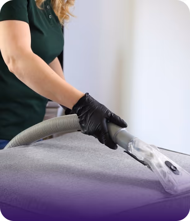 Person wearing black gloves cleaning a carpet with a professional vacuum hose.