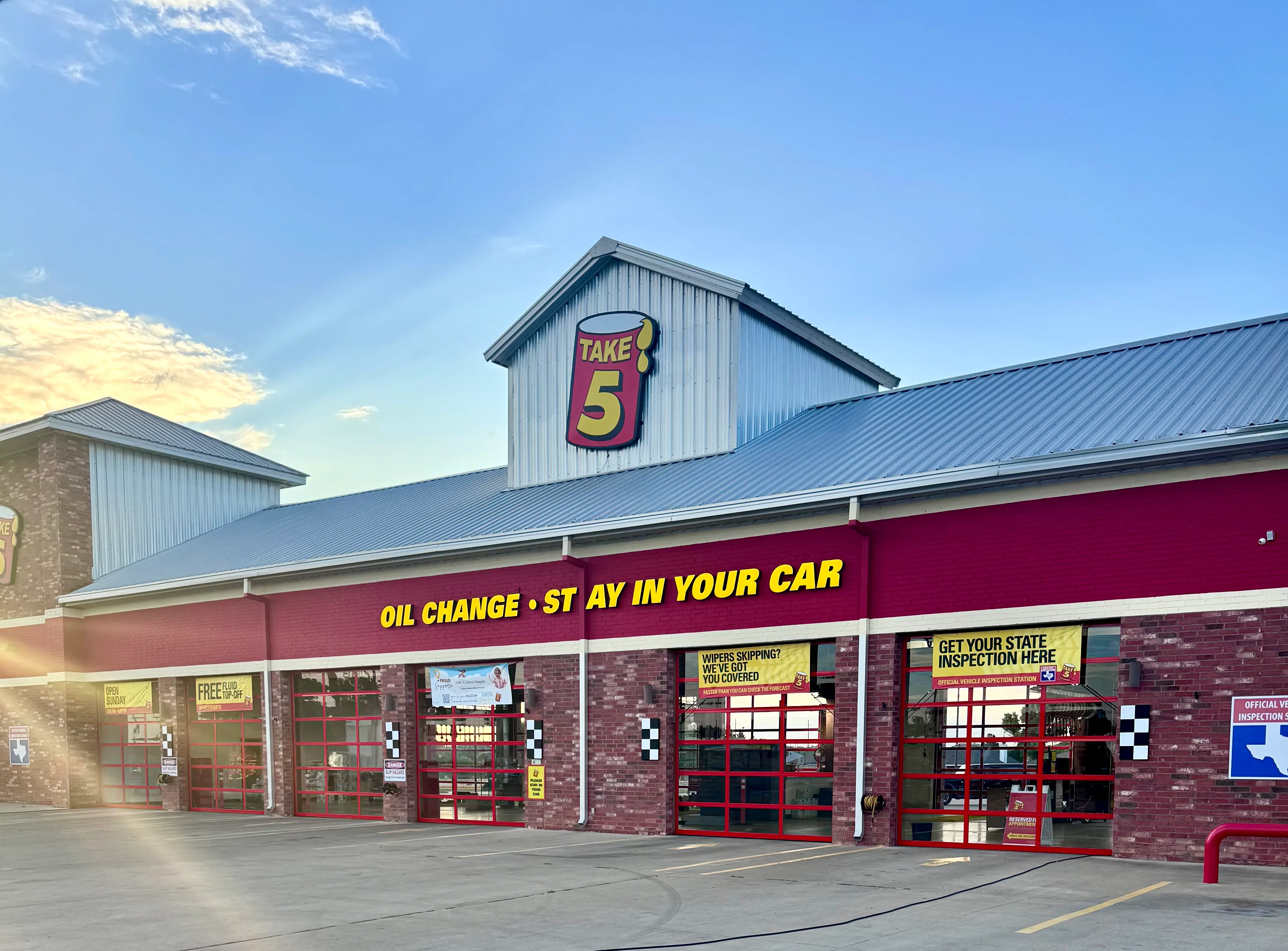 Take 5 auto service center with red garage doors and yellow signs offering oil changes and state inspections.