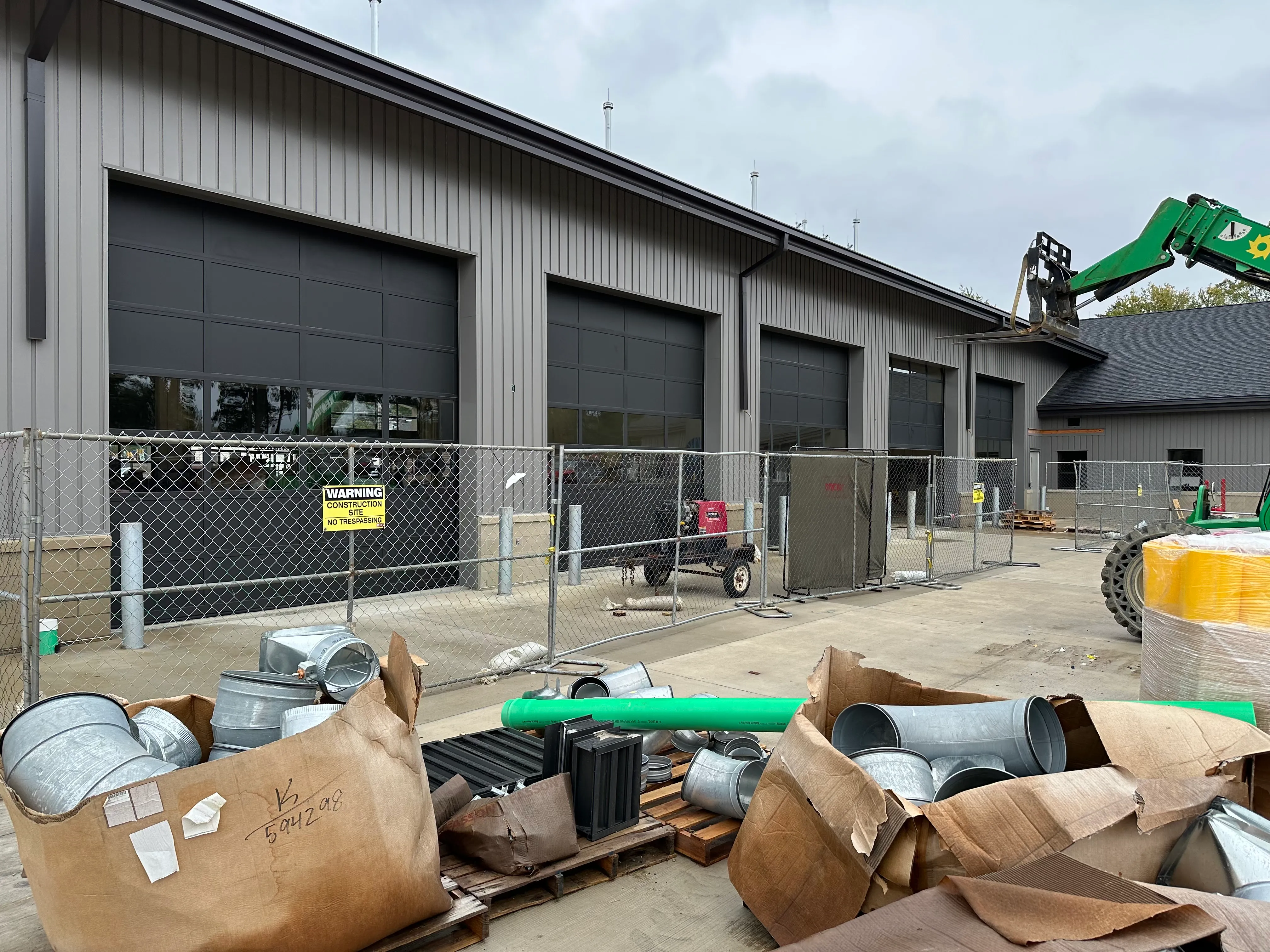 Interior view of an industrial garage with a partially open Wayne Dalton roll-up door, showing a wooden fence and a brick building outside.