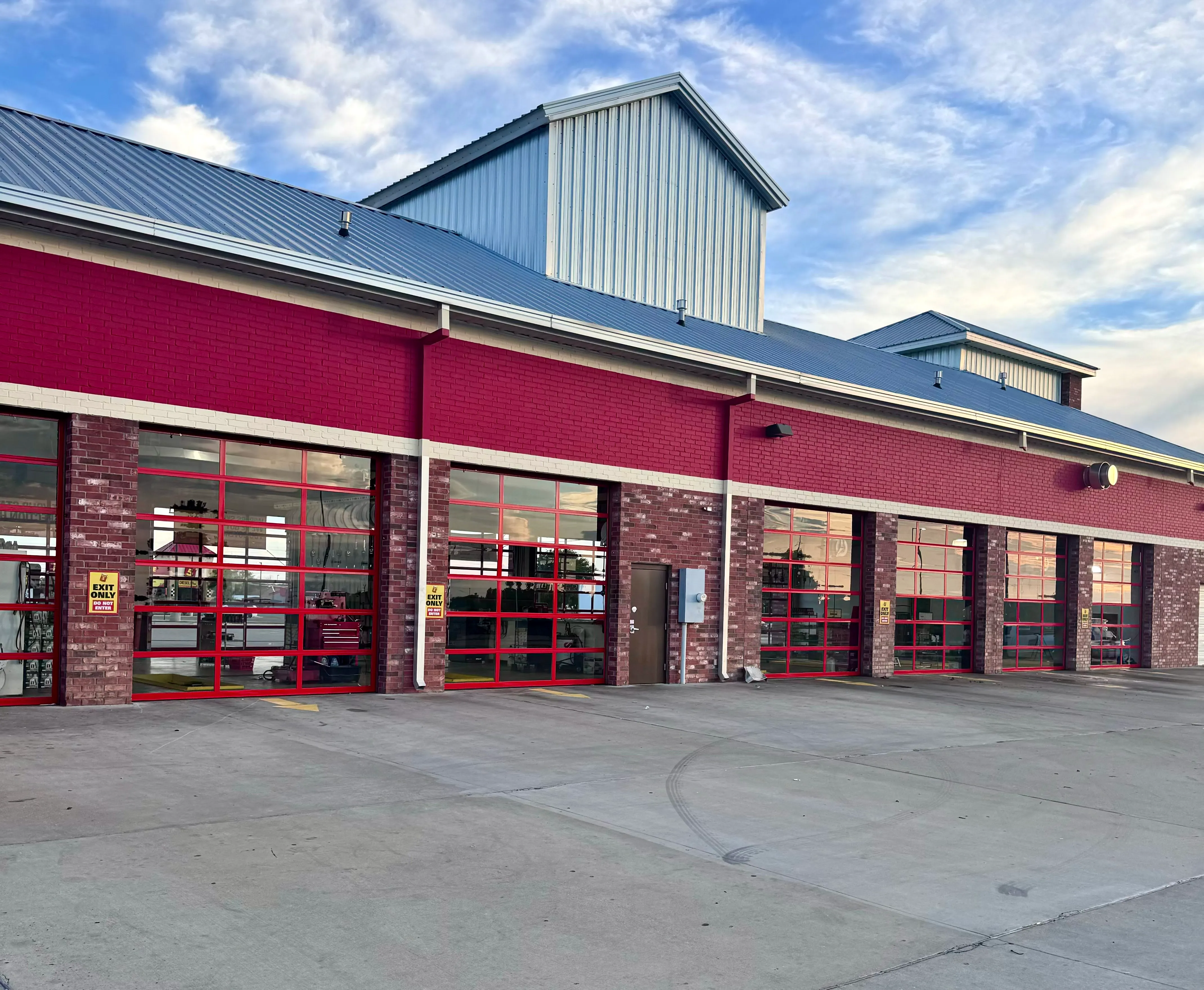 Three numbered loading dock doors with black protective padding and concrete pavement in front.