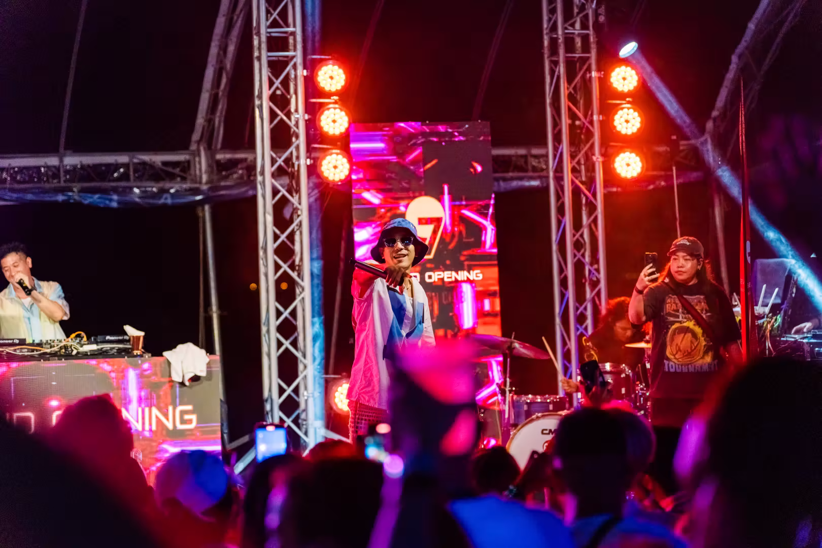 Musicians performing on stage at a night event with colorful lights and a crowd capturing the moment.