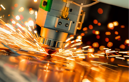 Industrial laser cutting metal sheet with bright sparks flying.