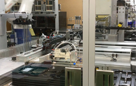 Various metal and plastic mechanical parts arranged on a gray surface, including gears, rings, and cylindrical components.