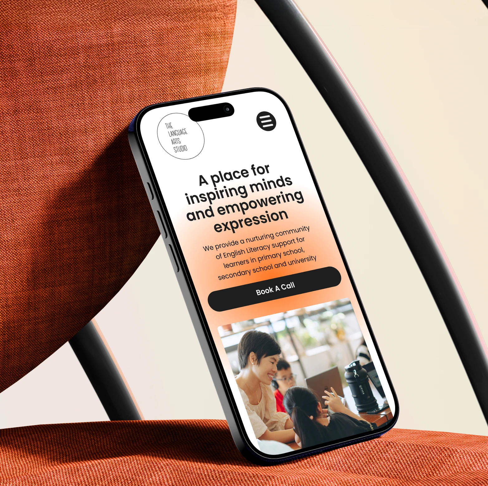 Smartphone displaying a website for The Language Arts Studio, featuring a tagline about inspiring minds and supporting English literacy learners, with a photo of a woman and children engaged in learning.