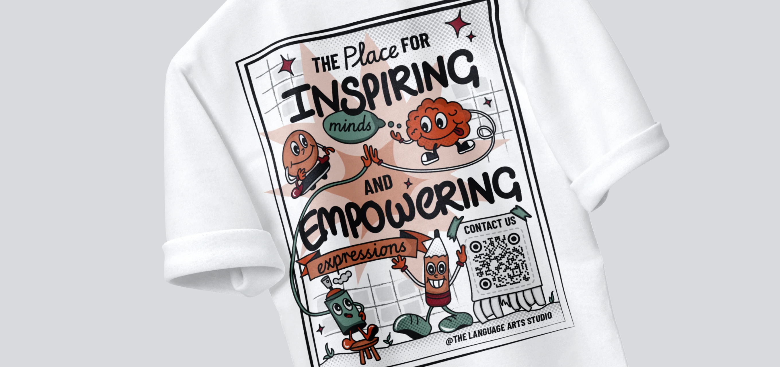 White t-shirt with colorful cartoon characters and text saying 'The place for inspiring minds and empowering expressions' including a QR code and '@The Language Arts Studio'.