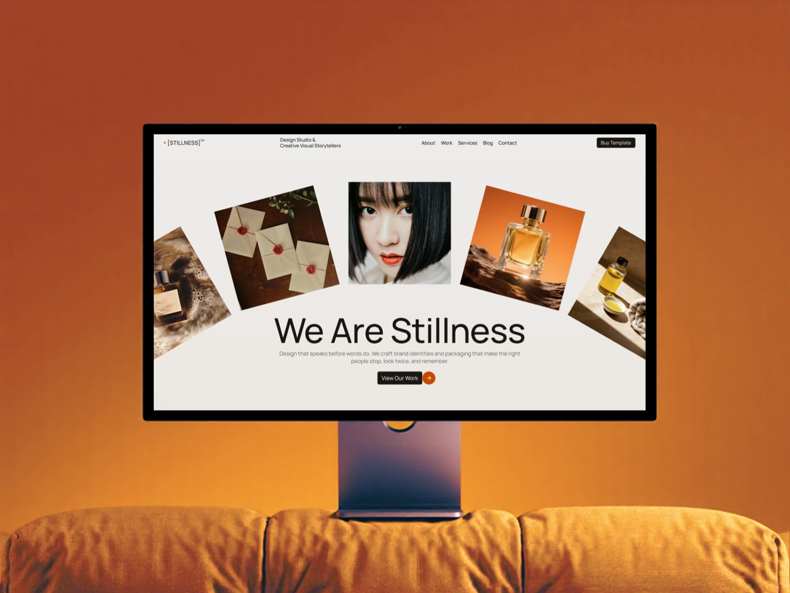 Computer monitor on orange couch showing Stillness design studio webpage with images and text from the Stillness Webflow Template created by Guilty as Foxx