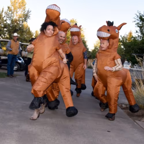 A group of people in costumes running down a street.