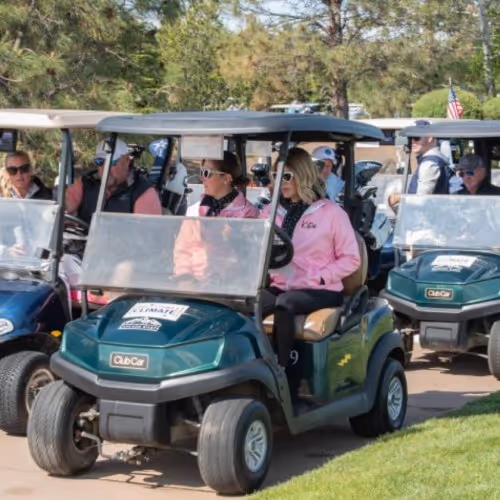 A group of people riding golf carts down a road.