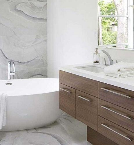 Modern bathroom with a freestanding white bathtub, wood-paneled vanity with sink, and a window overlooking greenery.