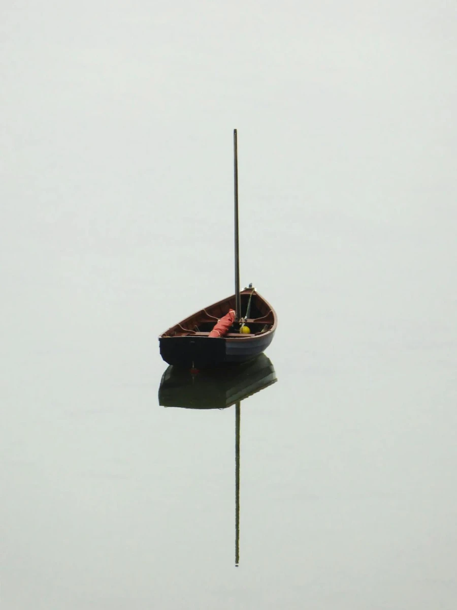 Minimal photo of a small floating object reflected on calm water.
