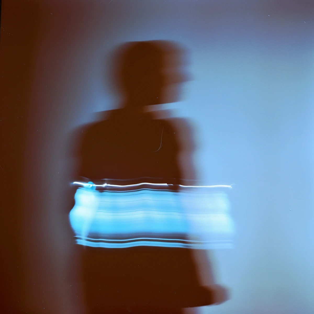 Motion-blur photo of a person walking with a glowing blue band of light around their torso.