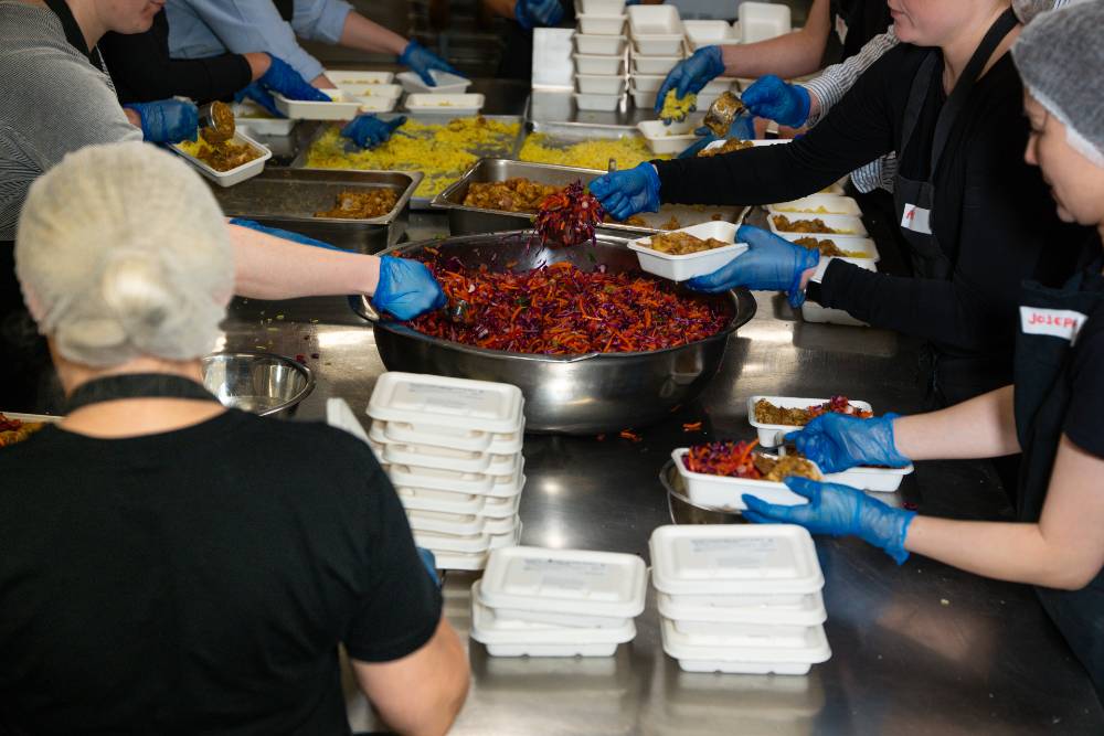 Volunteers in the Alex Makes Meals kitchen packing healthy meals into individual portions