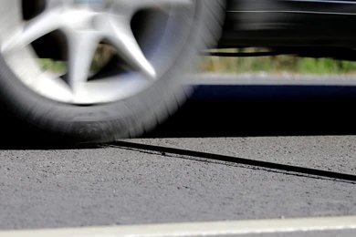 Close-up of a car wheel in motion passing over a road crack.