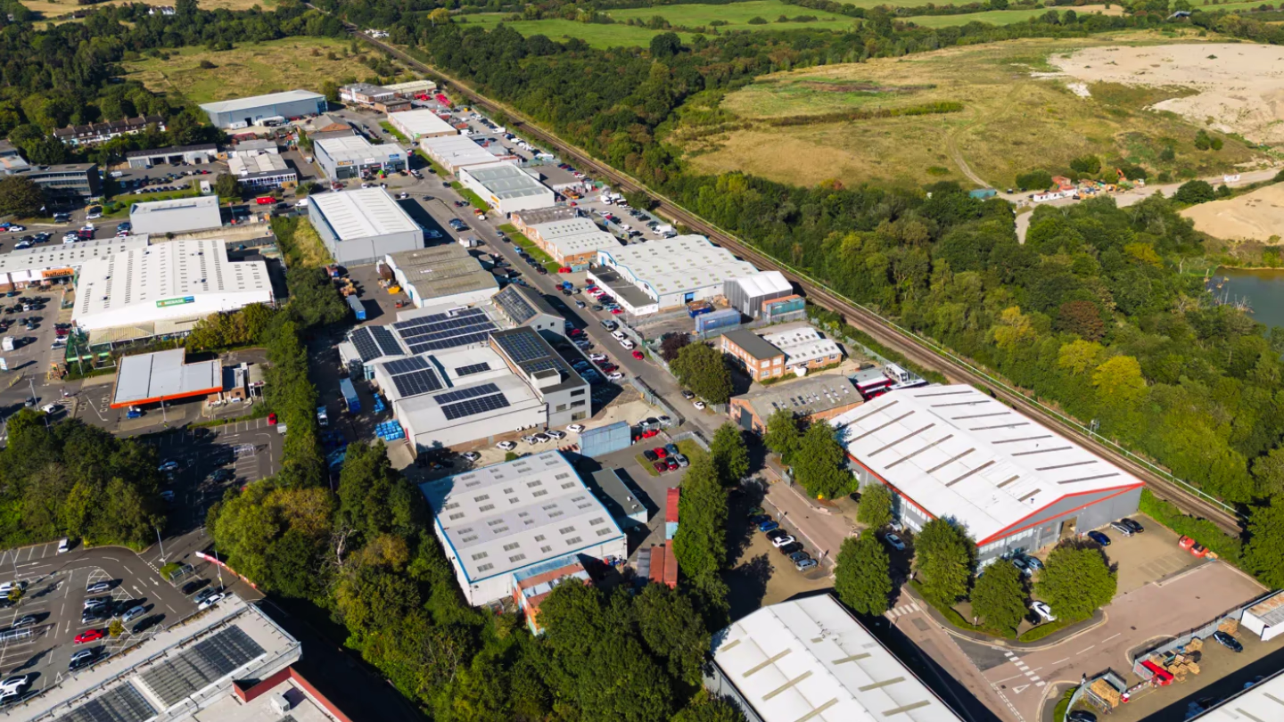 Aerial view of an industrial park with warehouse buildings, parking lots, and surrounding greenery.