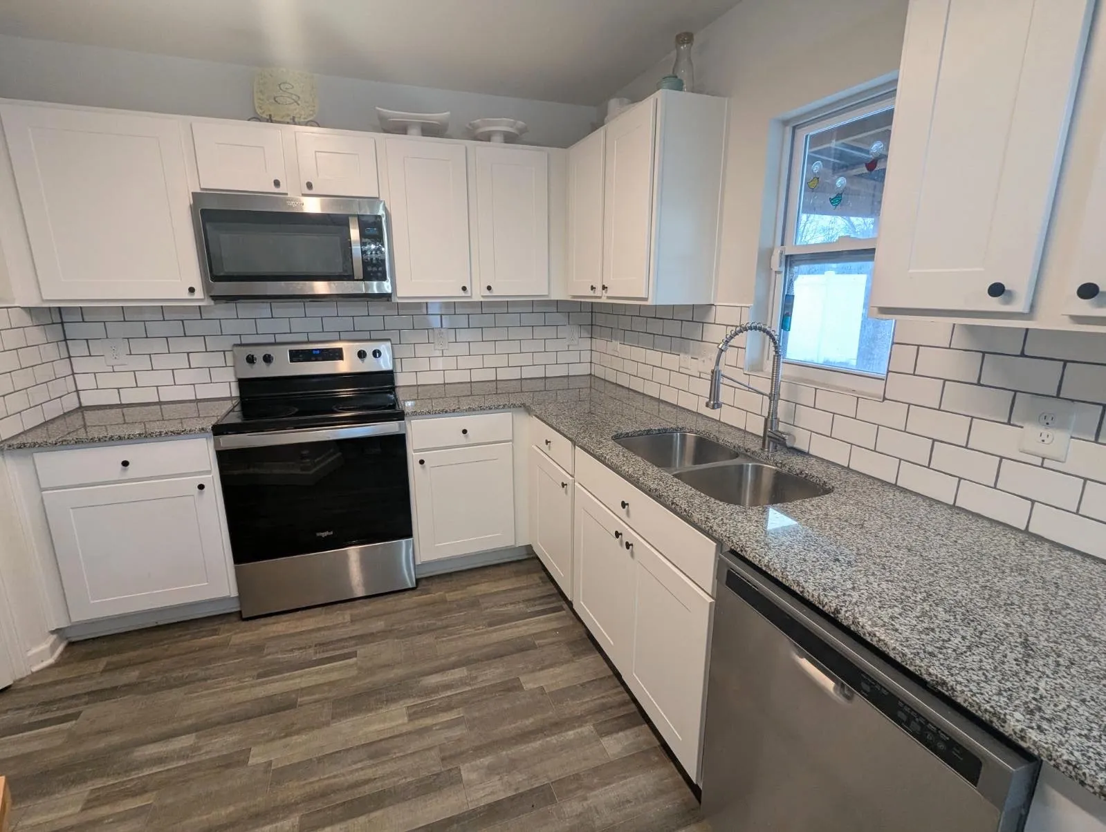 A beautiful white tile backsplash that has been added right above the countertops of a Greenville, NC kitchen