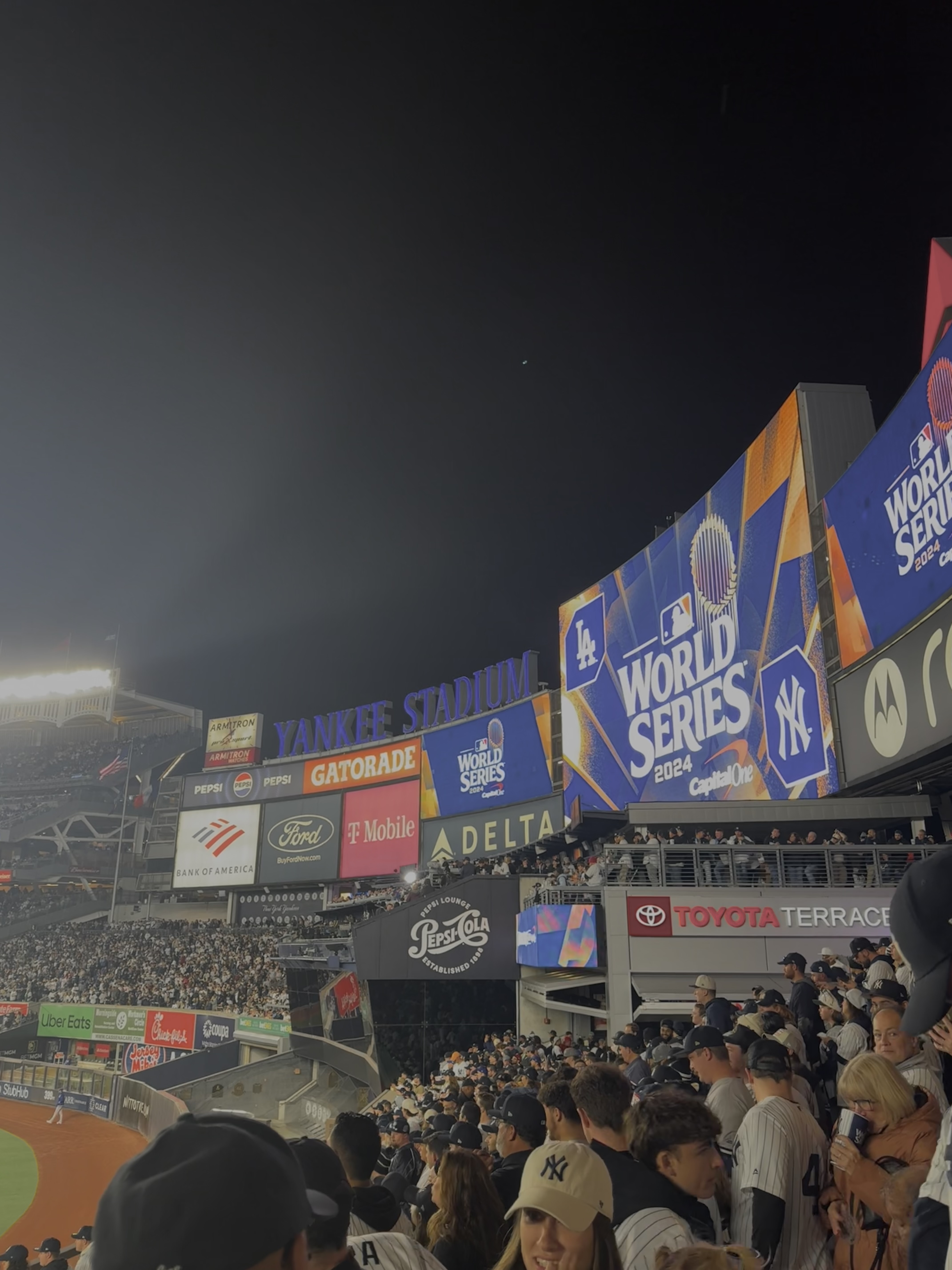 Crowd of fans at Yankee Stadium during the 2024 MLB World Series between the Los Angeles Dodgers and New York Yankees at night.