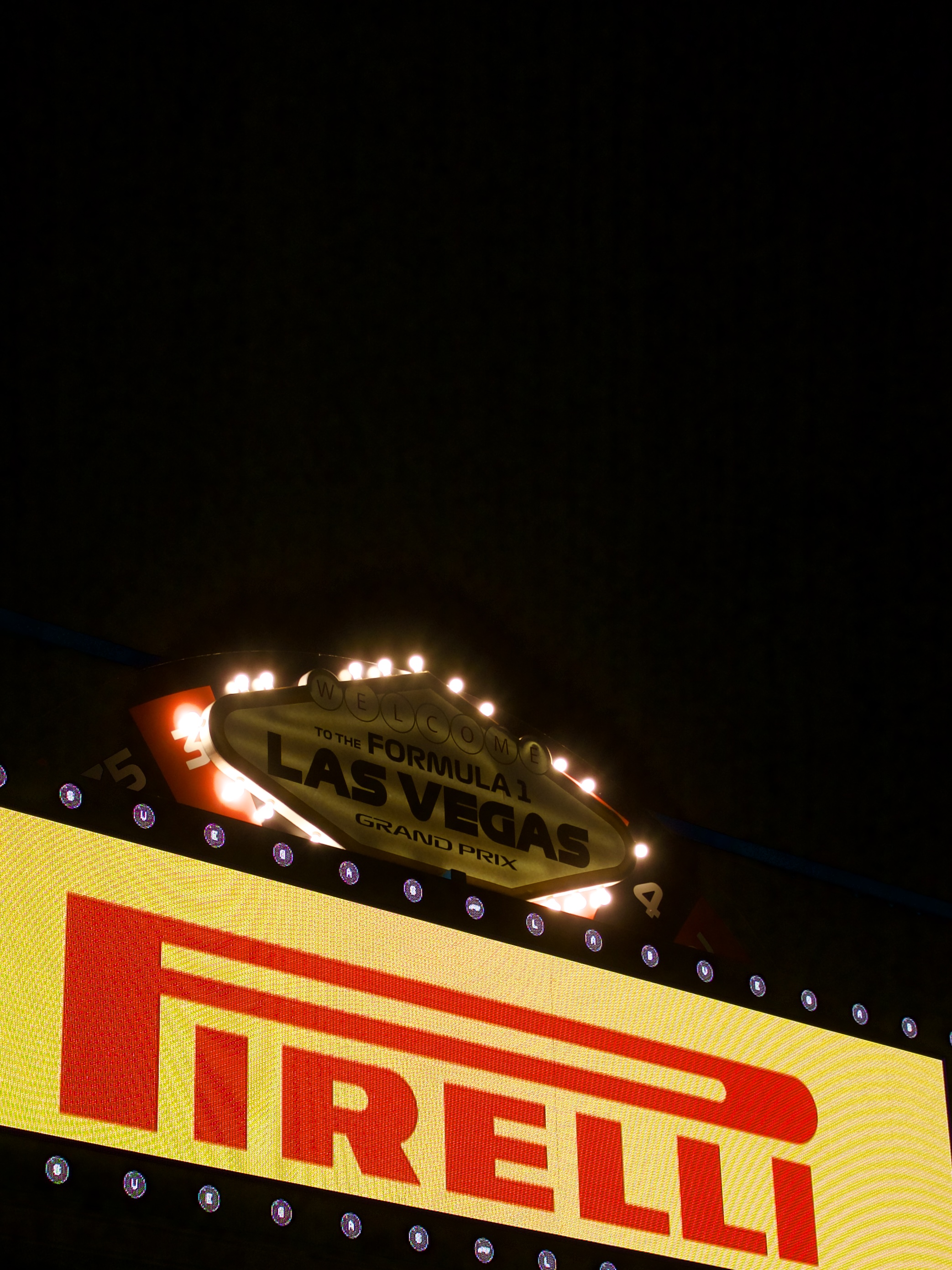 Illuminated sign reading 'Welcome to the Formula 1 Las Vegas Grand Prix' above a bright Pirelli advertisement at night.