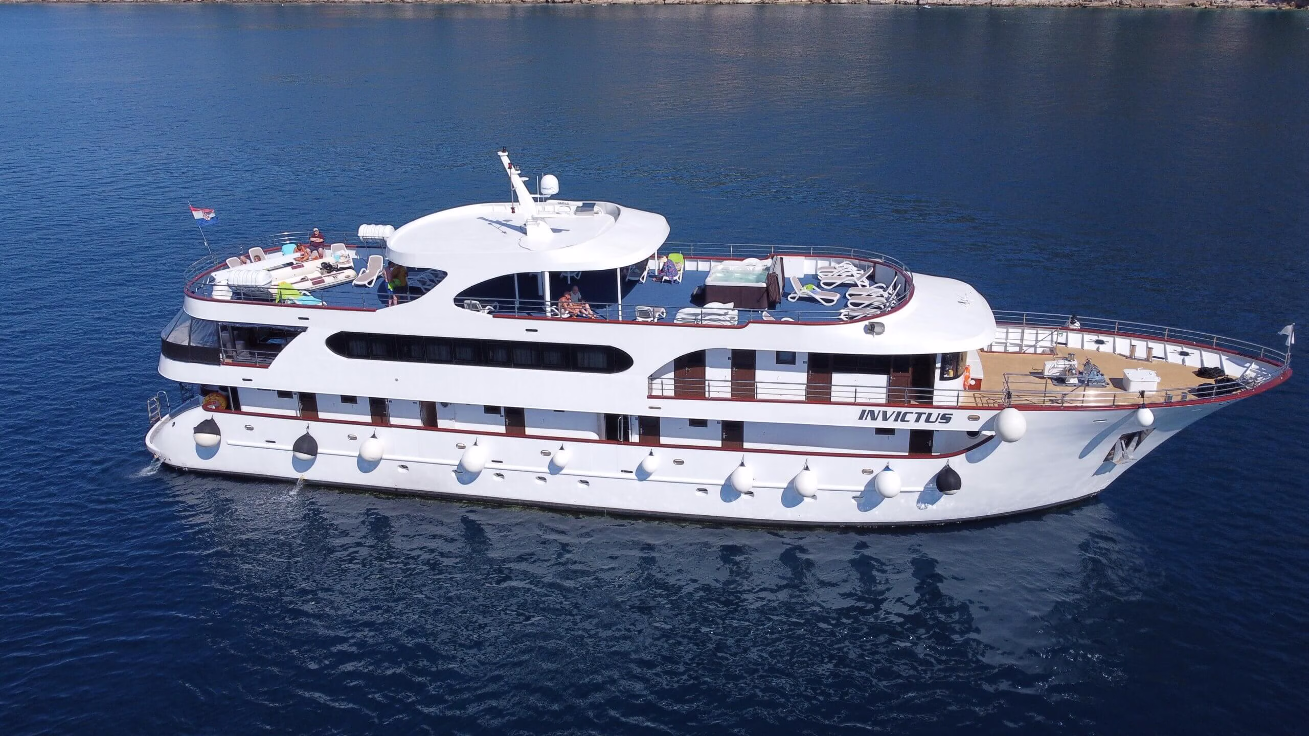 Aerial view of the small cruise ship with guests on the sun deck