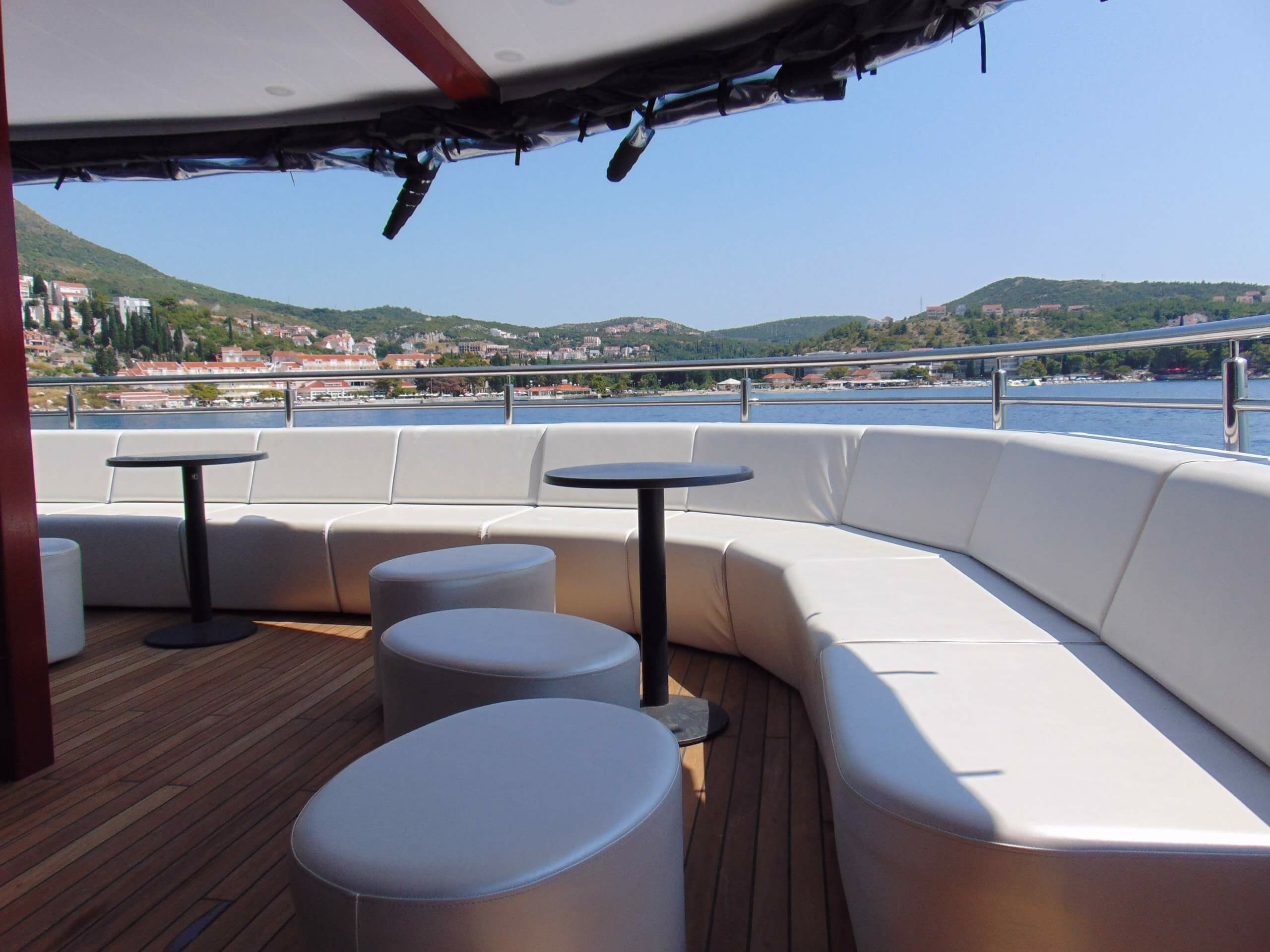Curved white deck sofa with bar tables and harbour view