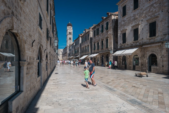 Stradun in Dubrovnik with families strolling towards the bell tower
