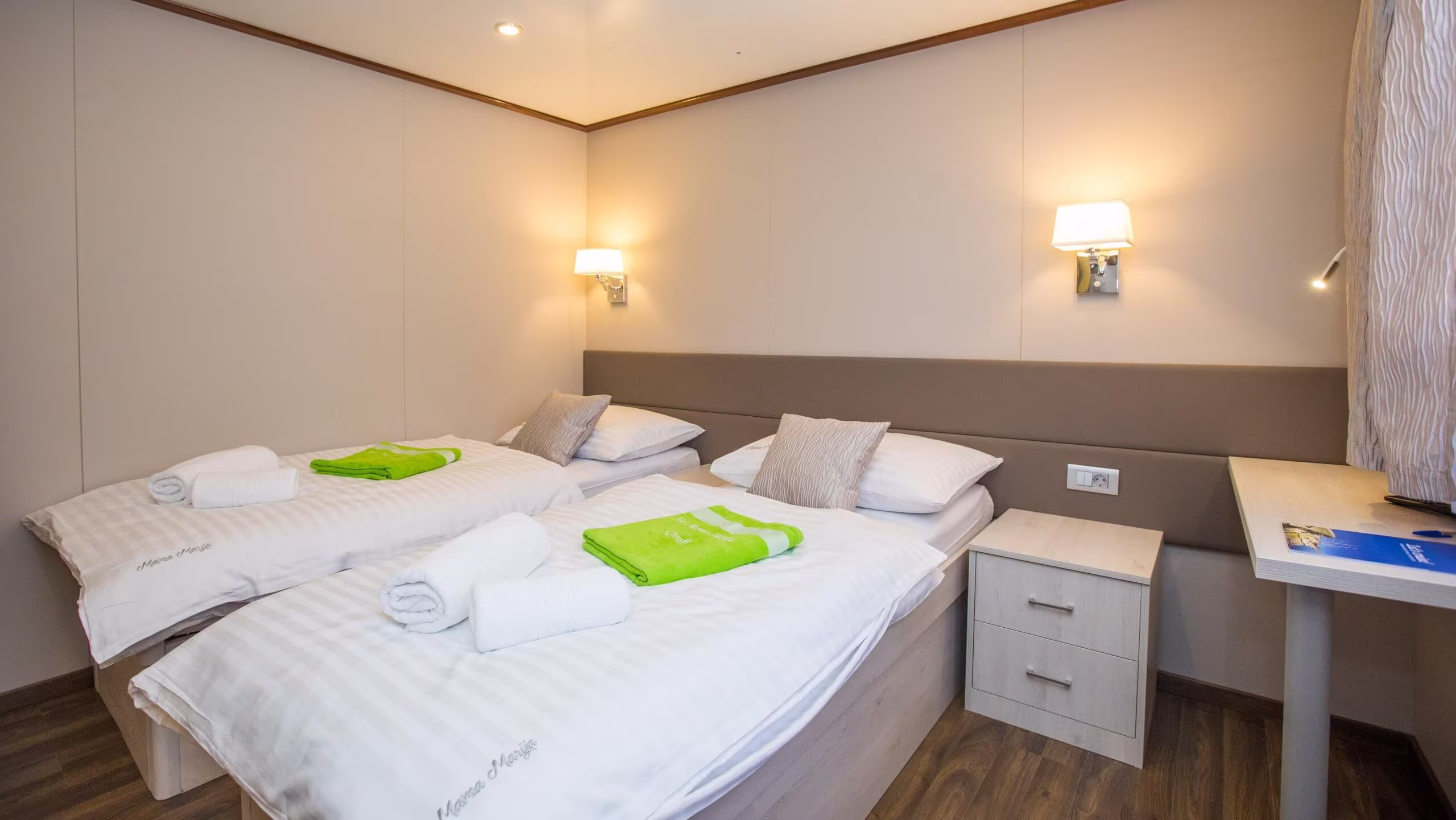 Twin cabin with lime green towels and bedside drawers